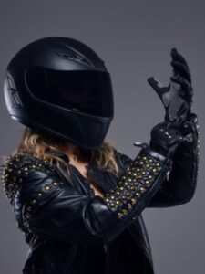portrait-biker-girl-wearing-leather-racer-costume-protective-helmet-putting-gloves-studio-gray-background